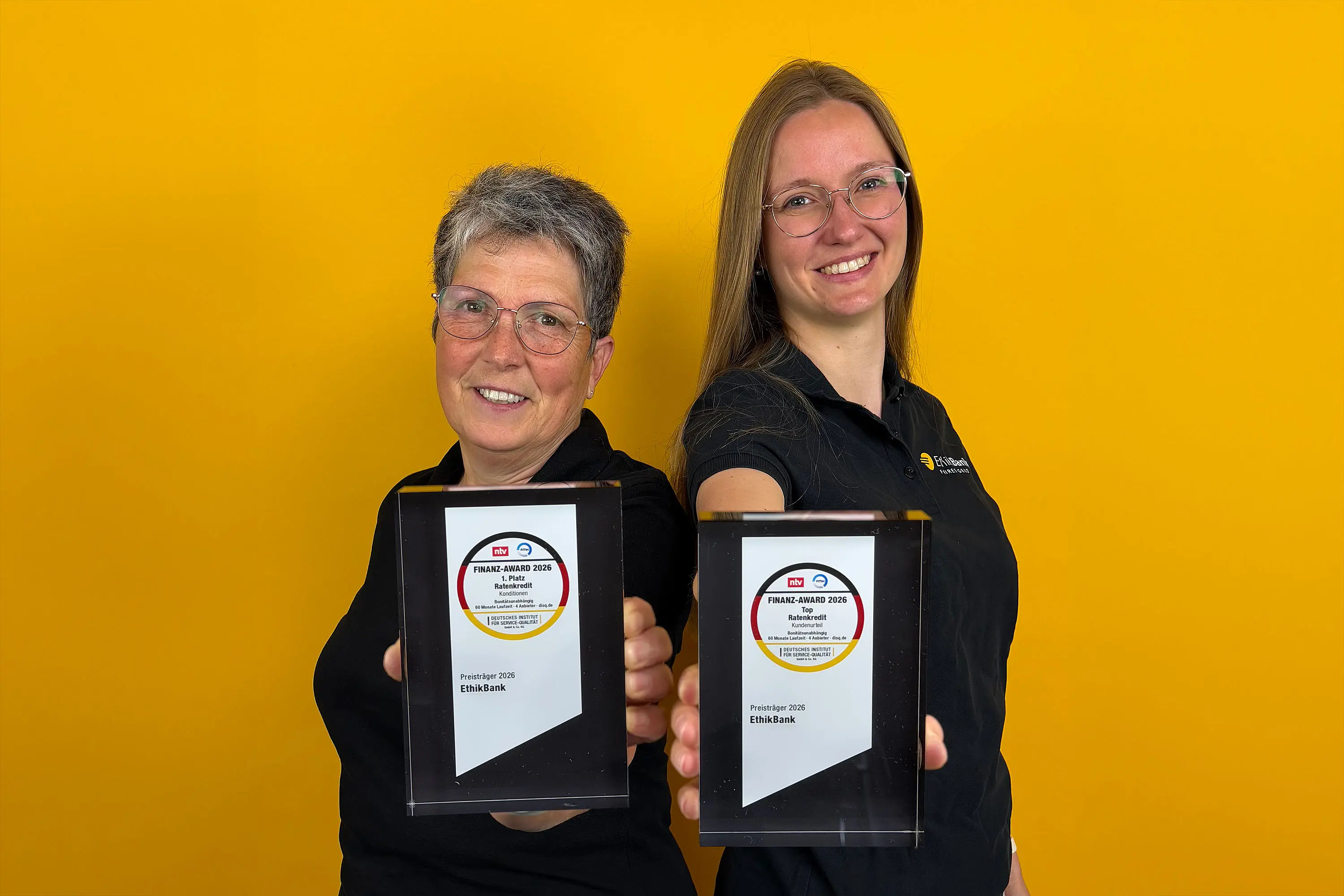 Zwei unserer Mitarbeiterinnen halten die Finanz-Awards 2026 in die Kamera