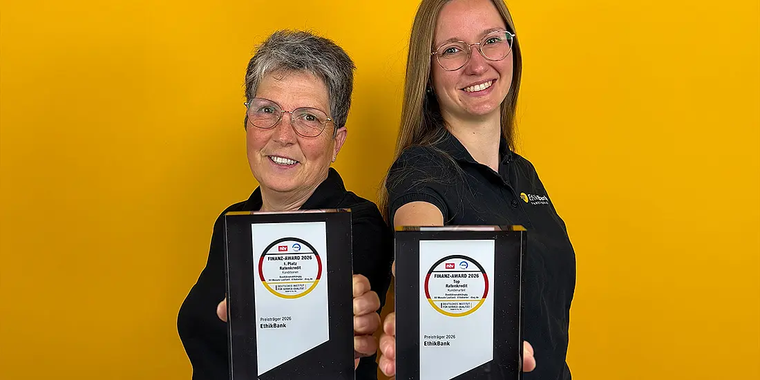 Zwei EthikBank-Mitarbeiterinnen halten lächelnd die zwei Finanz-Awards in die Kamera