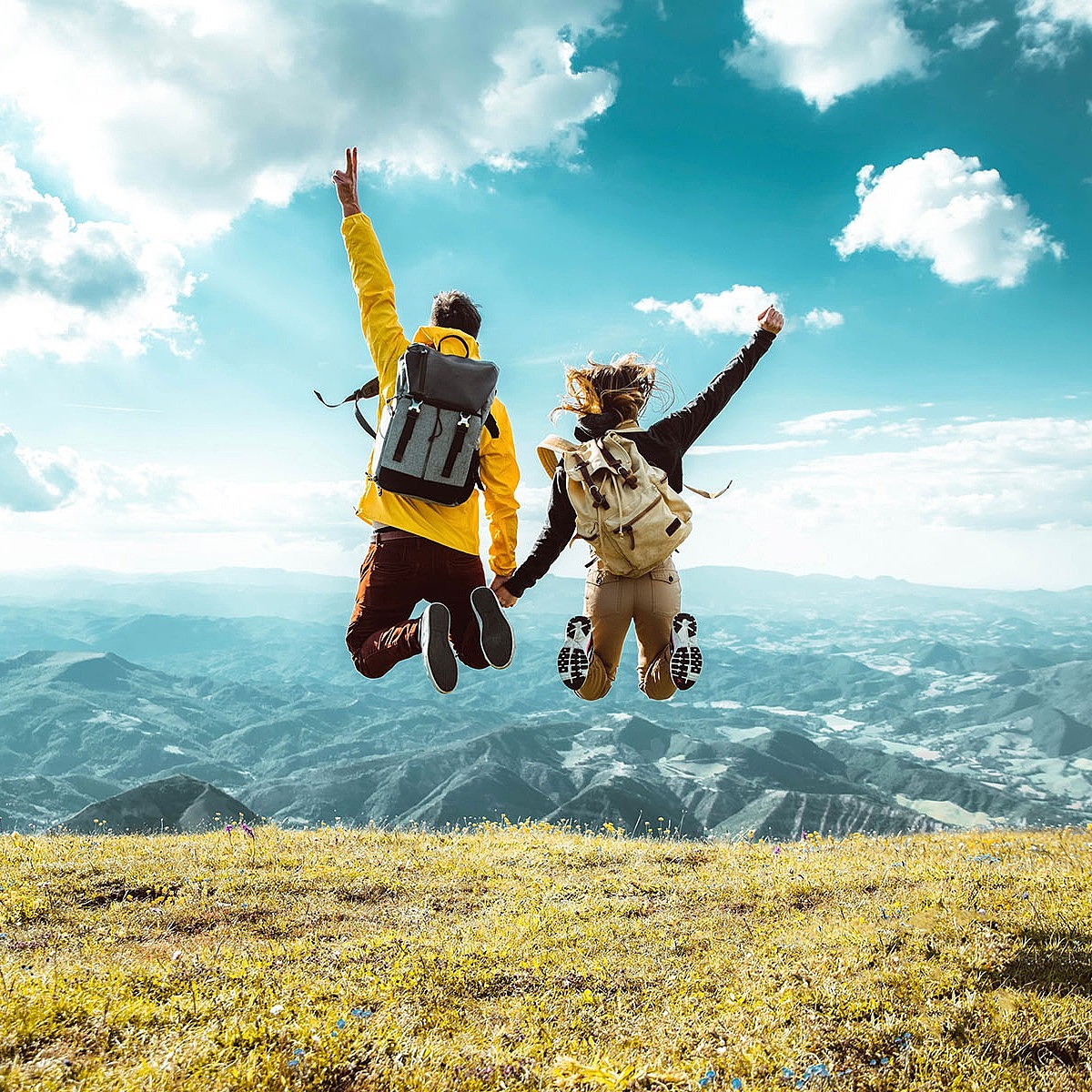 Ein Paar springt vor einer Bergkulisse vor Freude in die Luft