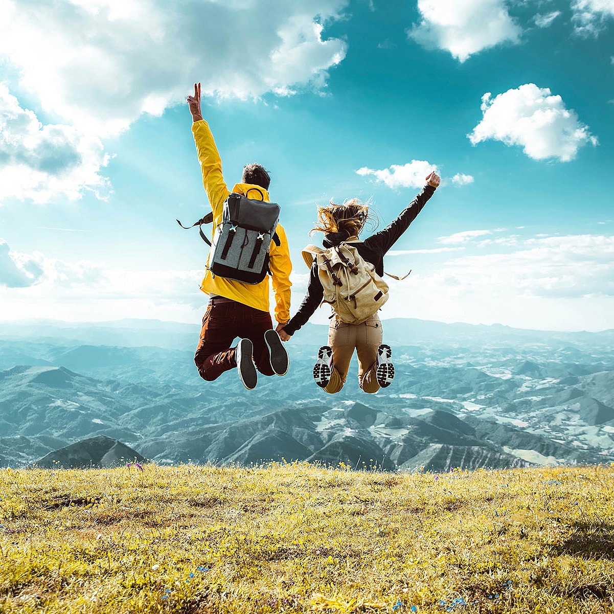 Ein Paar springt vor einer Bergkulisse vor Freude in die Luft