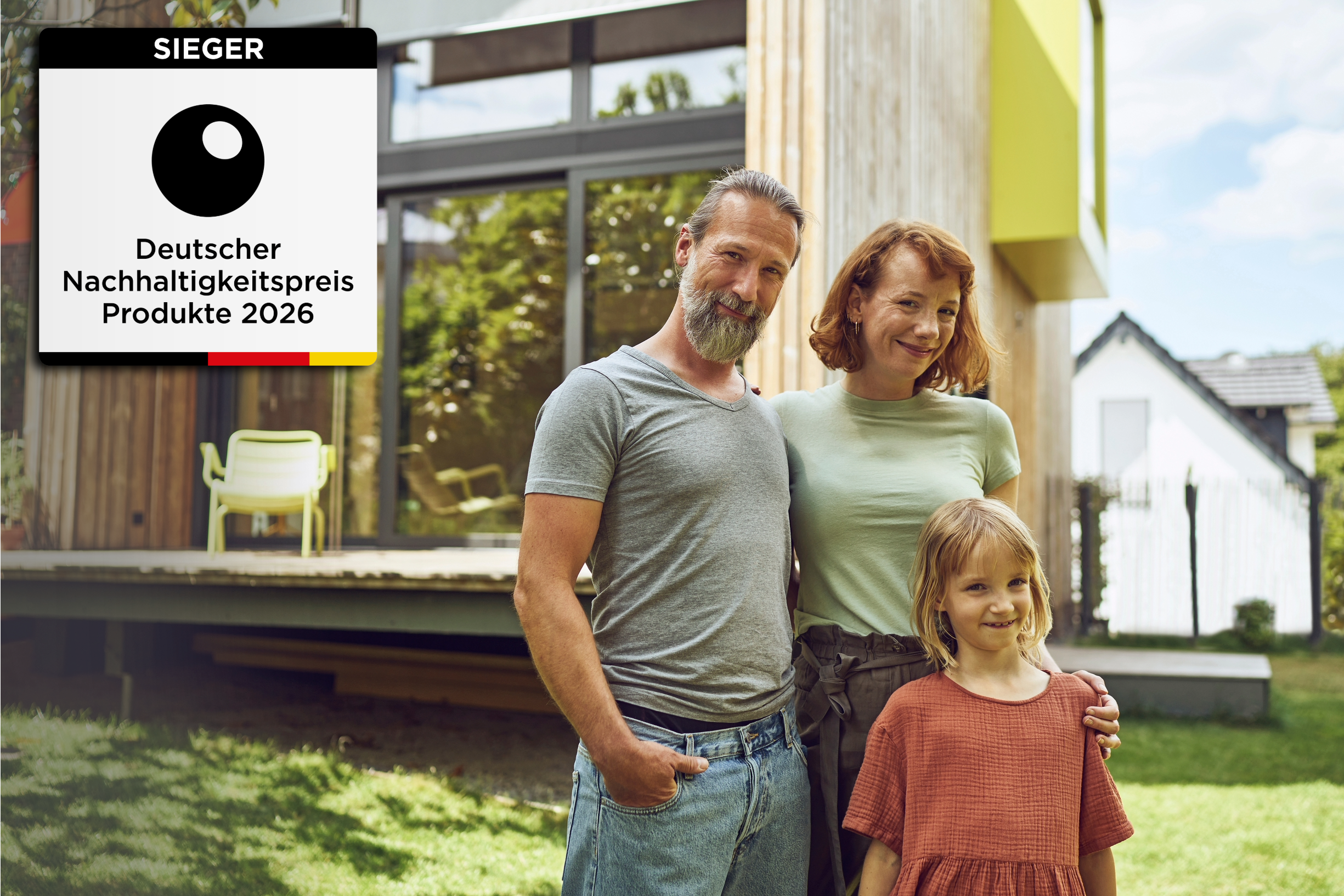 Junge Familie vor ihrem neu gebauten Haus und Siegel "Nachhaltigkeitspreis Produkte 2026"